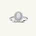 Sterling silver ring with oval moissanite center stone surrounded by double halo of sparkling stones on neutral background.