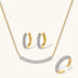 Gold-plated curved necklace, hoop earrings, and adjustable ring with pavé cubic zirconia stones on cream background.
