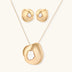 Close-up of organic gold-toned earrings and necklace with white baroque pearls on neutral background.