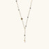 Y-shaped gold-plated necklace with white and gray freshwater pearls on cream background, showing adjustable drop design.