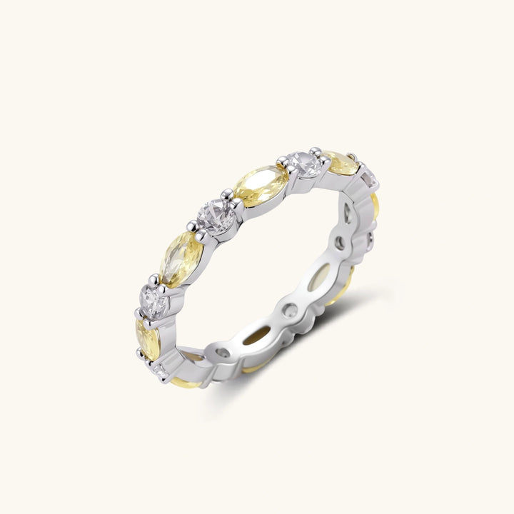 Platinum-plated copper ring with alternating clear and pale yellow oval stones in an eternity band design on white background.