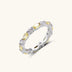 Platinum-plated copper ring with alternating clear and pale yellow oval stones in an eternity band design on white background.
